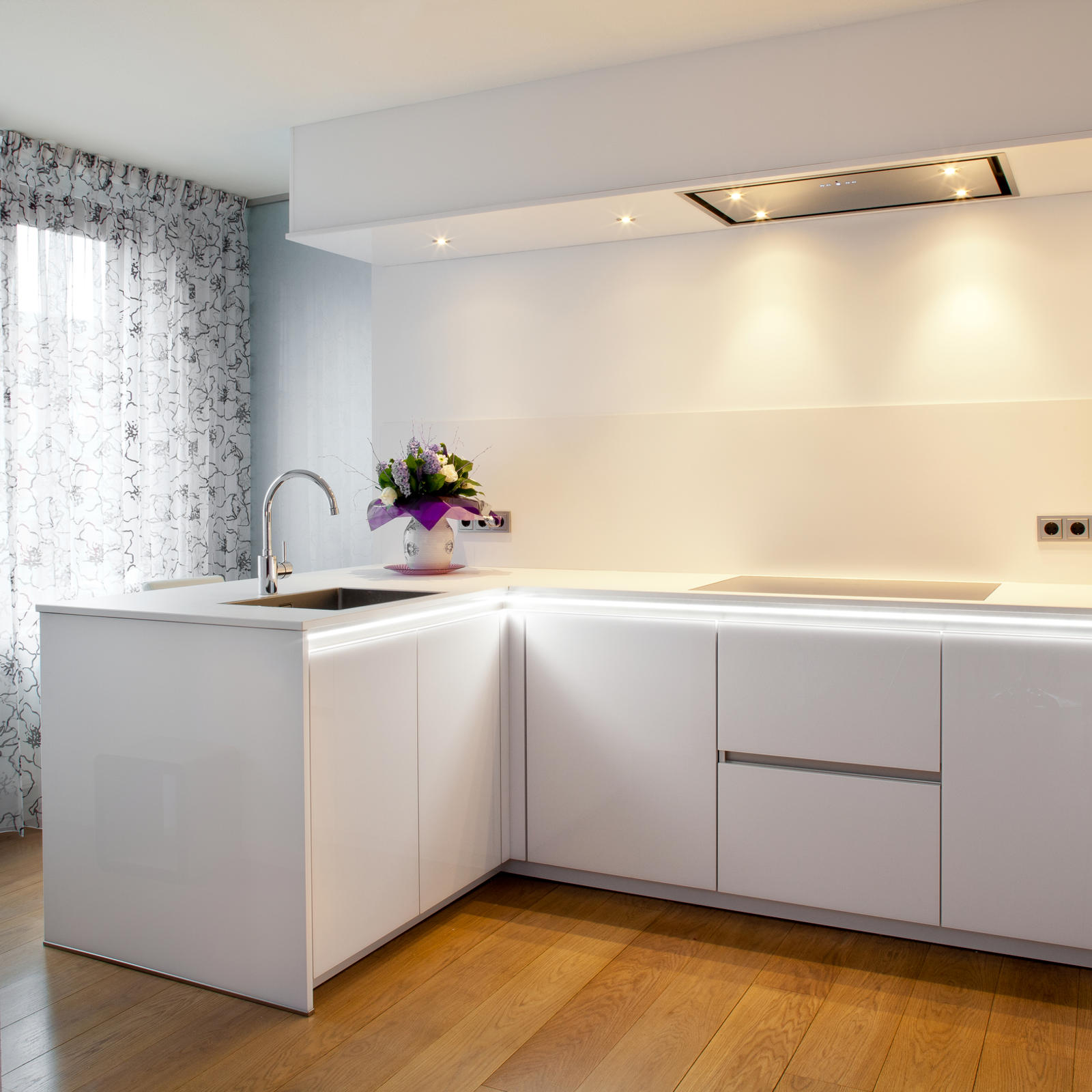 Designkeuken in Maastricht: witte hoogglans hoekkeuken met greeploze kasten en plafondafzuigkap