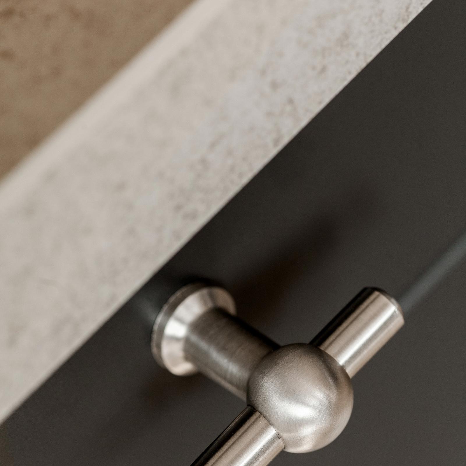 Close-up van een RVS T-knop op een antraciet lade onder het betonlook werkblad
