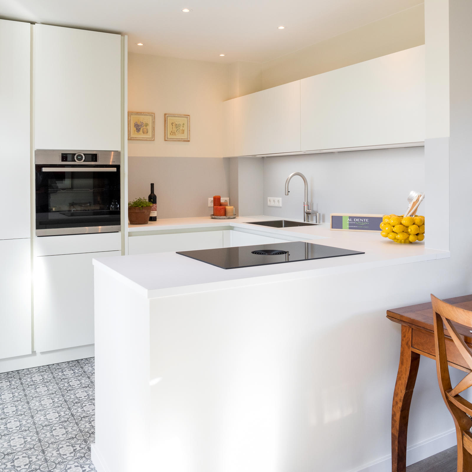 Witte keuken in Maastricht: witte greeploze keuken met schiereiland, inductiekookplaat en inbouwoven