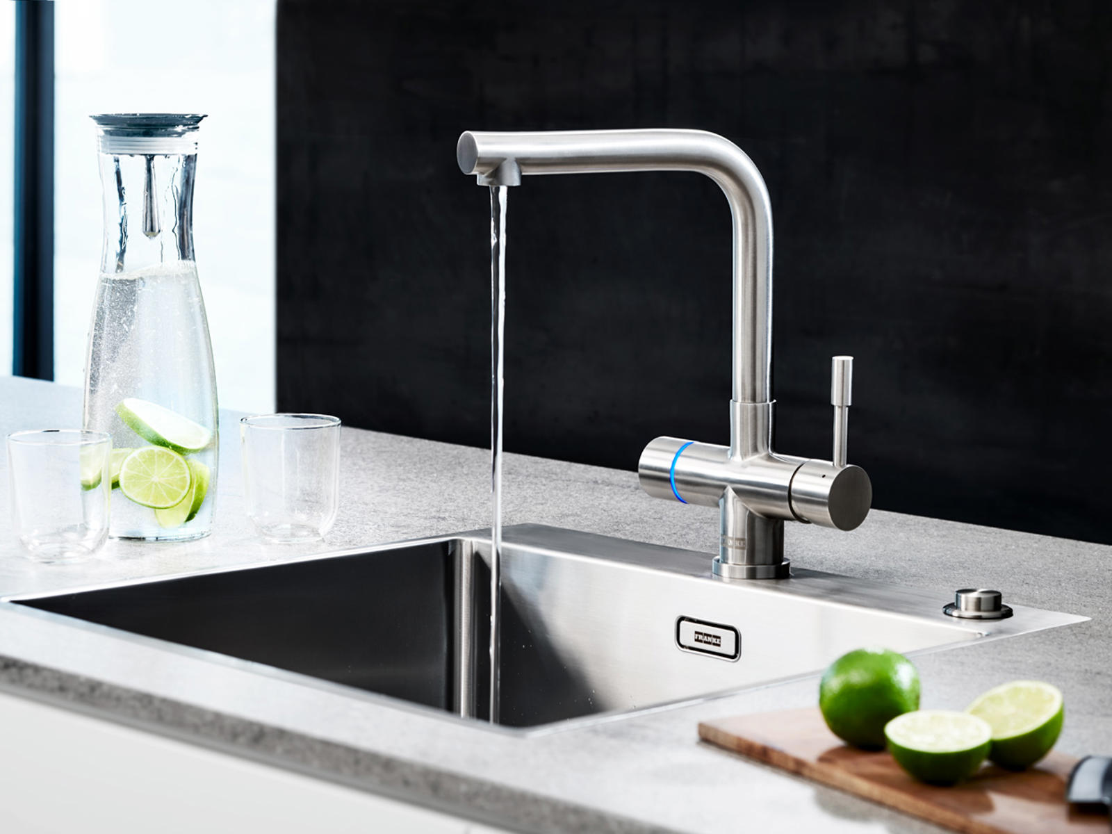 Franke rvs kraan met filterwater boven een spoelbak in een grijs stenen werkblad