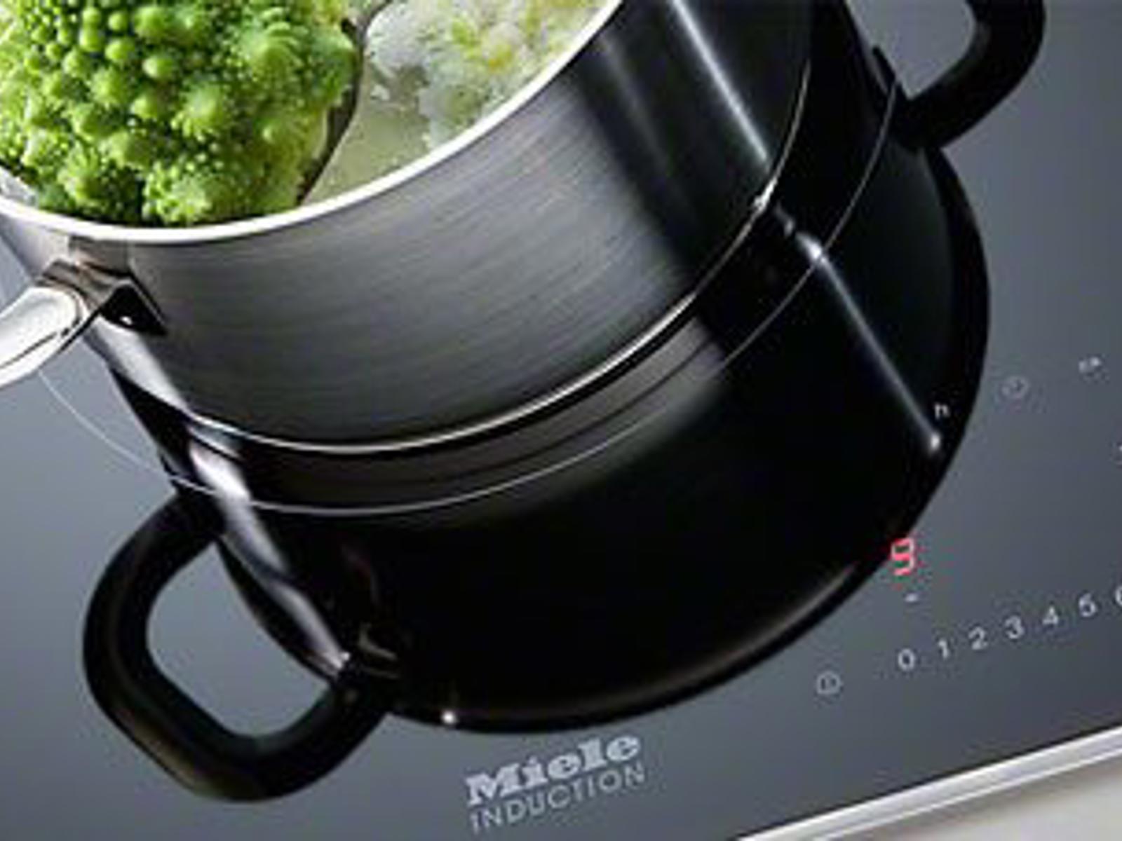 Miele inductiekookplaat met rvs kookpot en Romanesco, close-up van de bediening