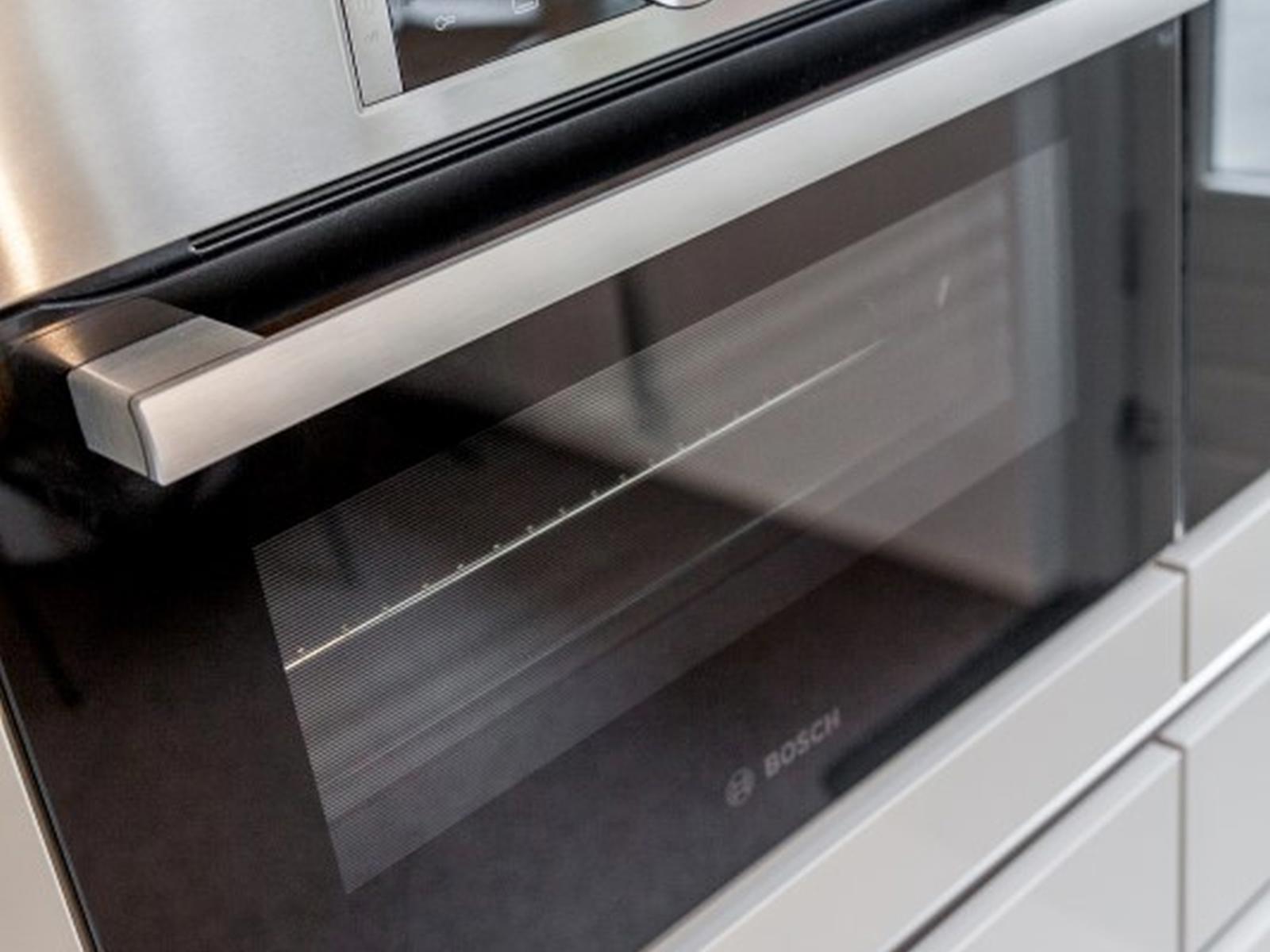 Bosch rvs inbouwoven met display in witte greeploze kastenwand
