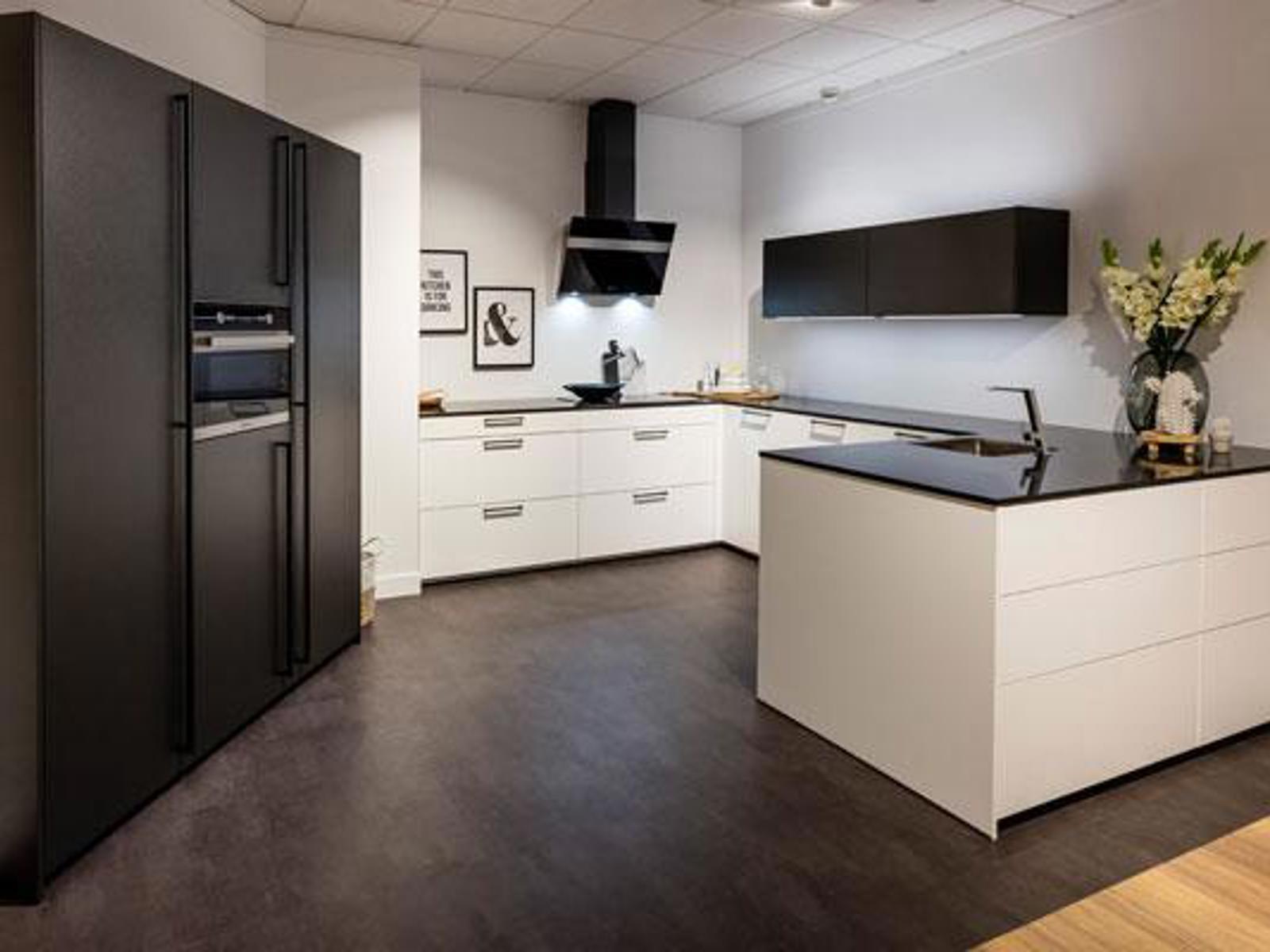 Showroomkeuken met zwarte hoge kasten, witte onderkasten, zwart werkblad en schiereiland