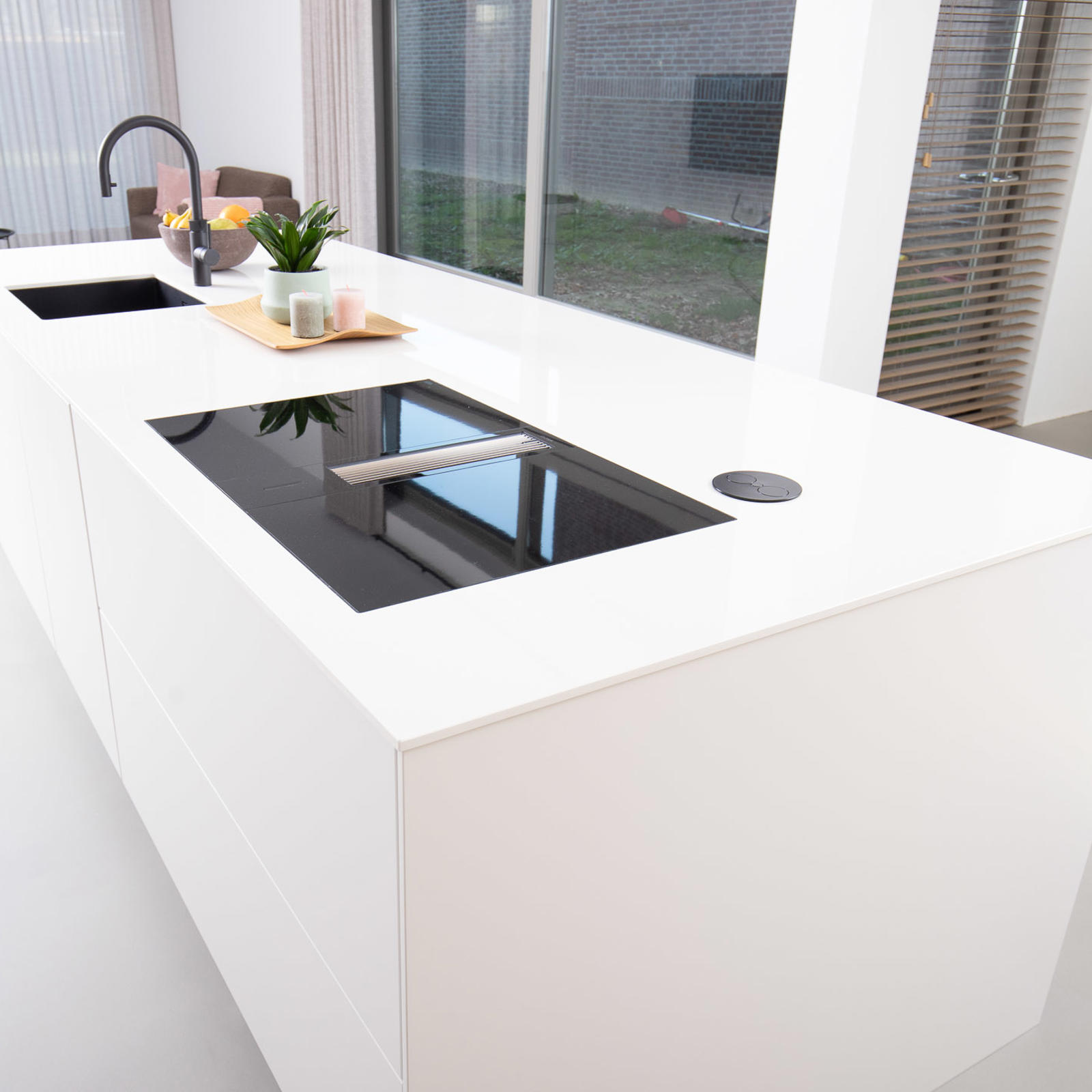 Strakke greeploze keuken in Eijsden: wit kookeiland met inductiekookplaat met afzuiging en spoelbak