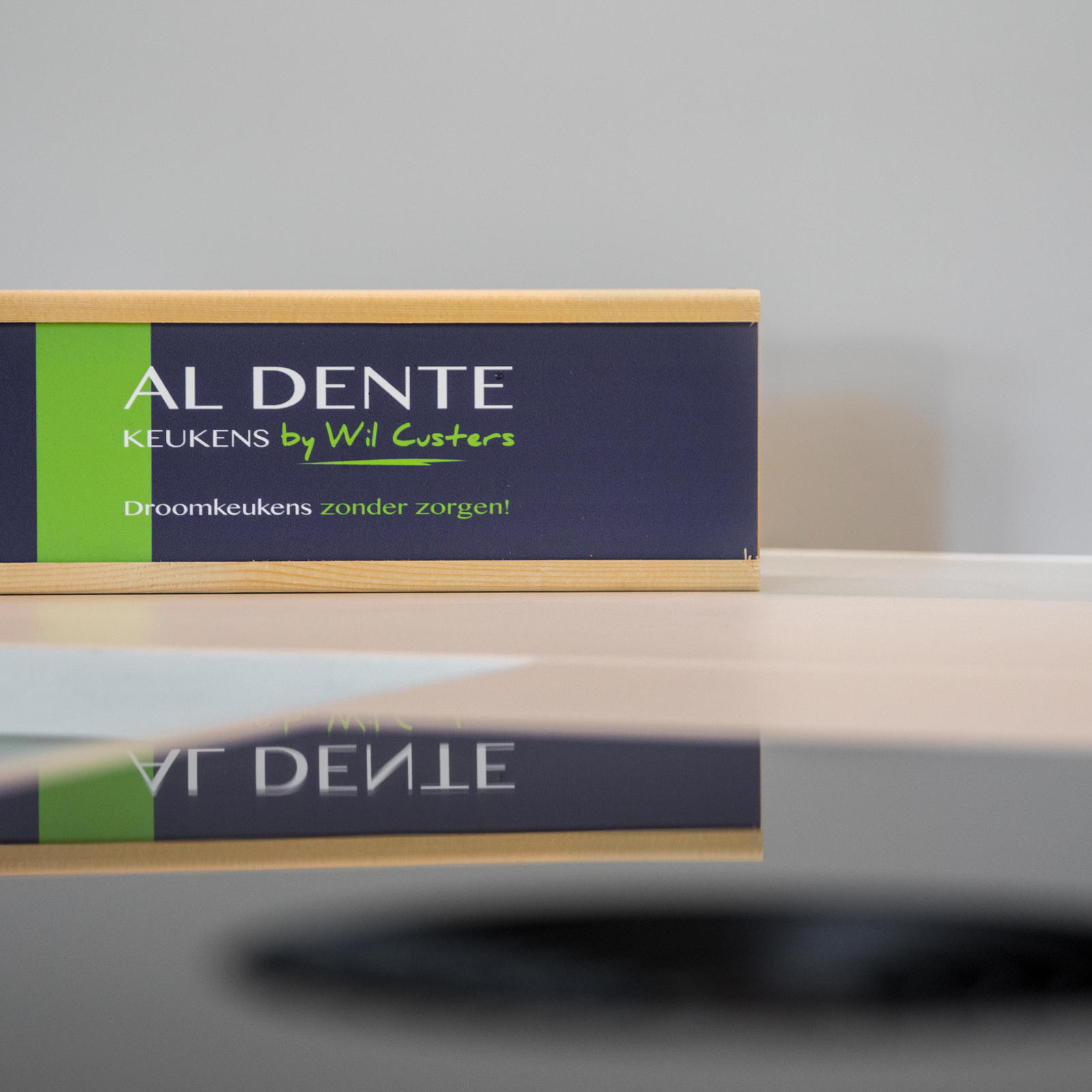 Al Dente Keukens naambordje weerspiegeld in een zwarte kookplaat