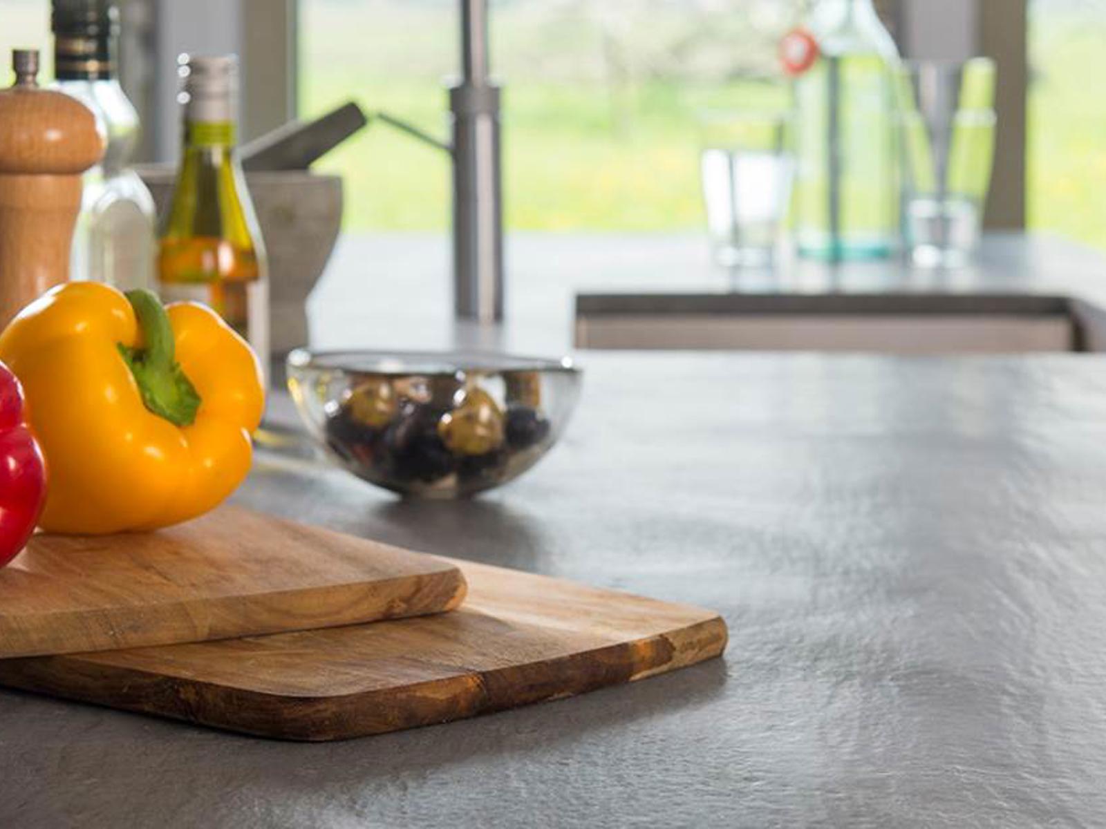 Kemie donker werkblad met snijplanken, paprika's en olijfolie voor een raam met tuinzicht