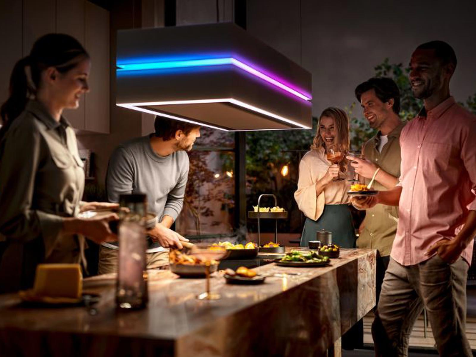 Berbel eilandafzuigkap met gekleurde ledverlichting boven een kookeiland met gezelschap aan tafel