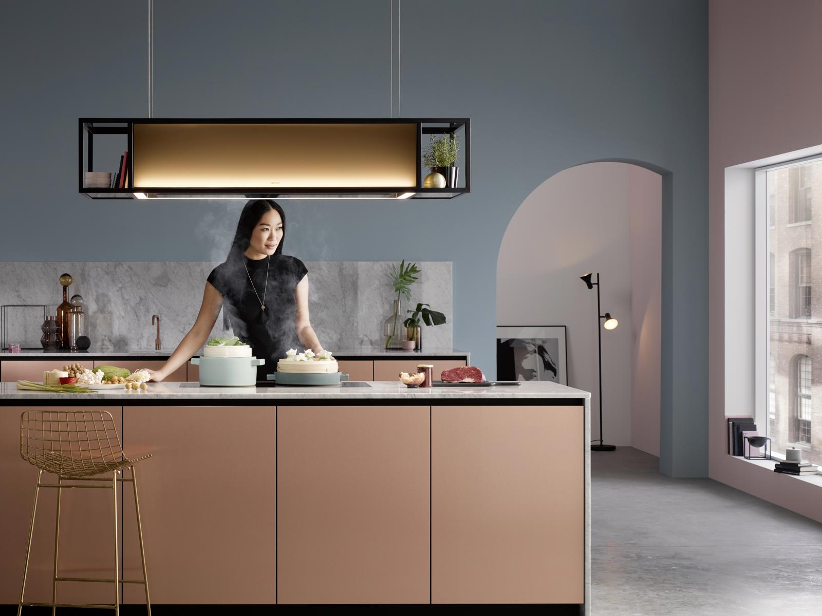 Berbel open frame-afzuigkap met verlichting boven een kookeiland met roze fronten