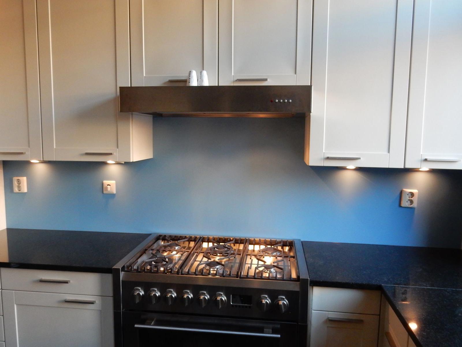 Bokmerk achterwand in blauw achter een gasfornuis met rvs afzuigkap en witte kasten