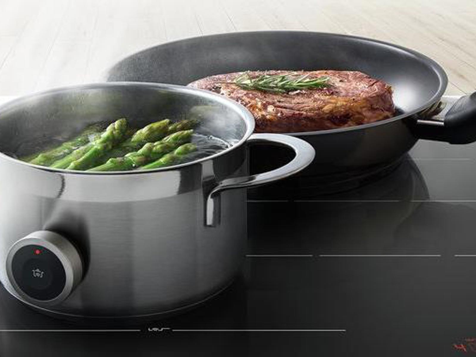 Bosch inductiekookplaat met kookpot met asperges en een pan met steak